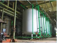 Industrial process tanks and green piping inside a plant